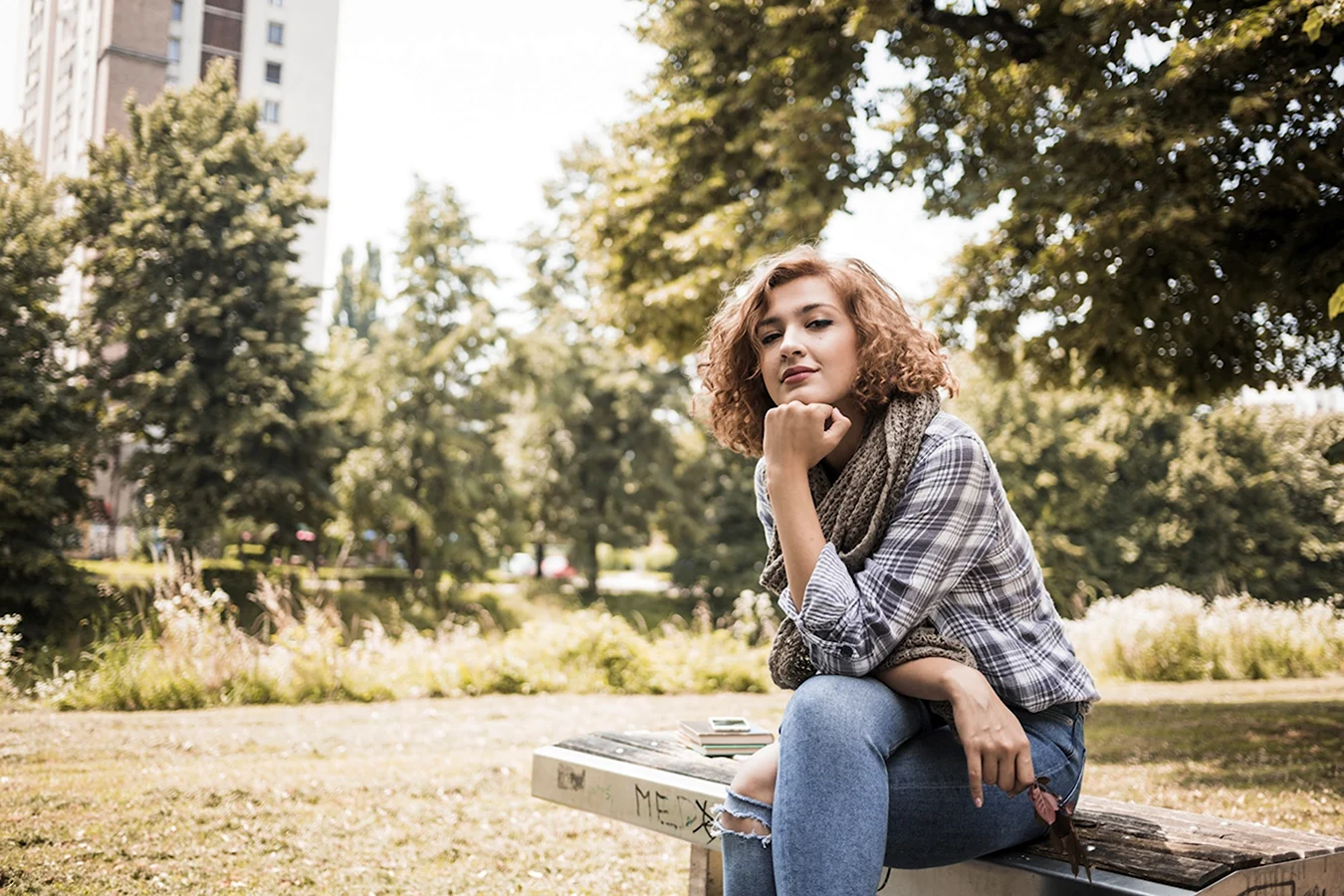 Девушка в джинсах на скамейк