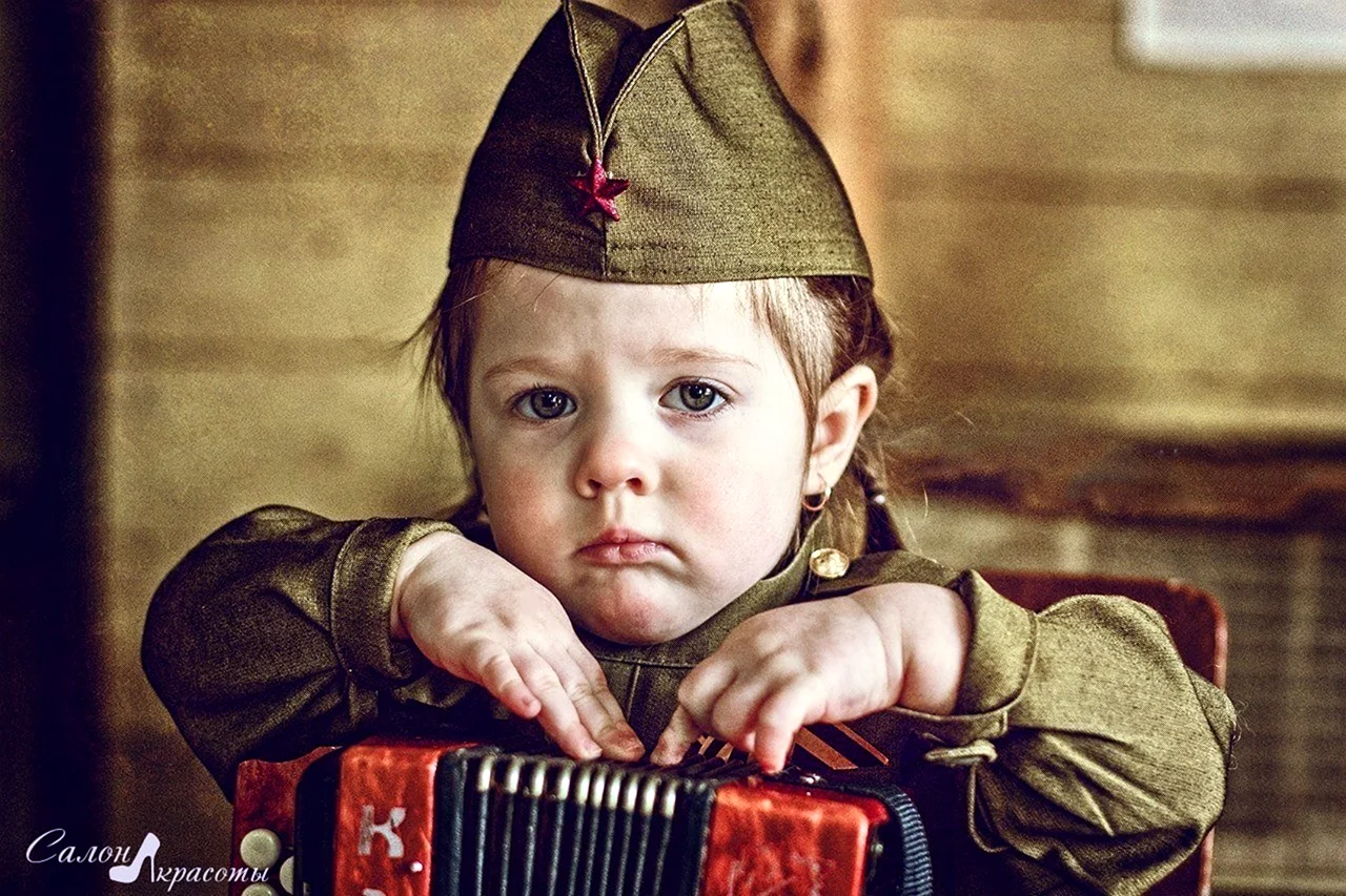 Ребёнок в военной форме с гармошкой